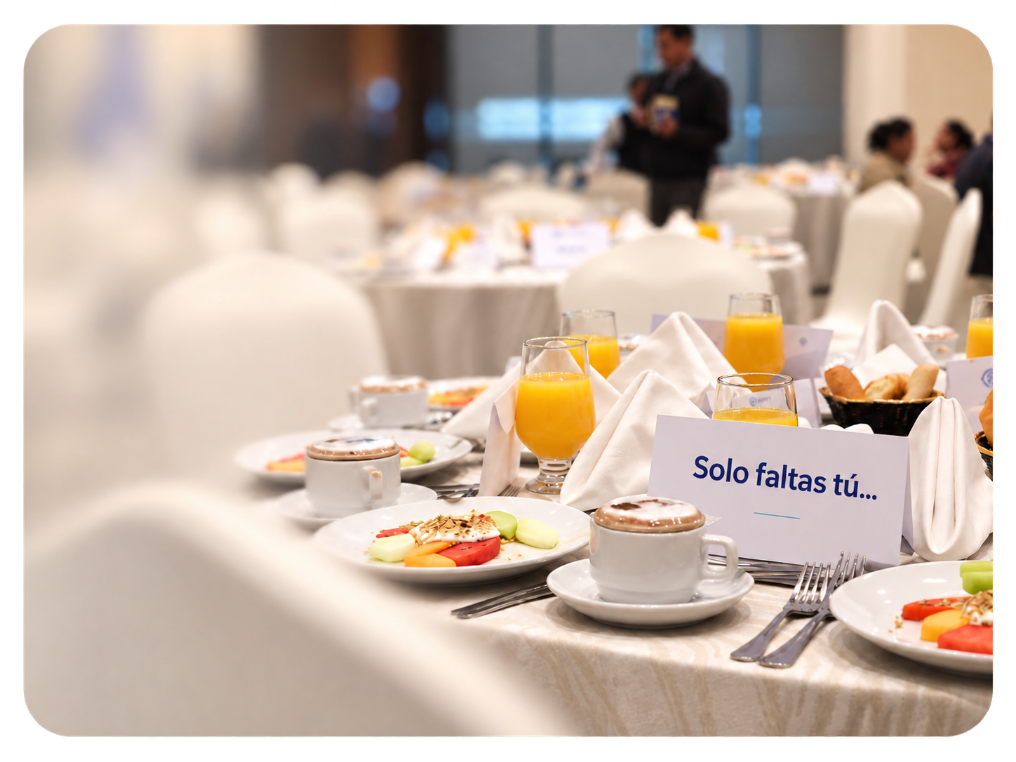 Mesa preparada para el desayuno empresarial con una tarjeta que dice Solo faltas tú
